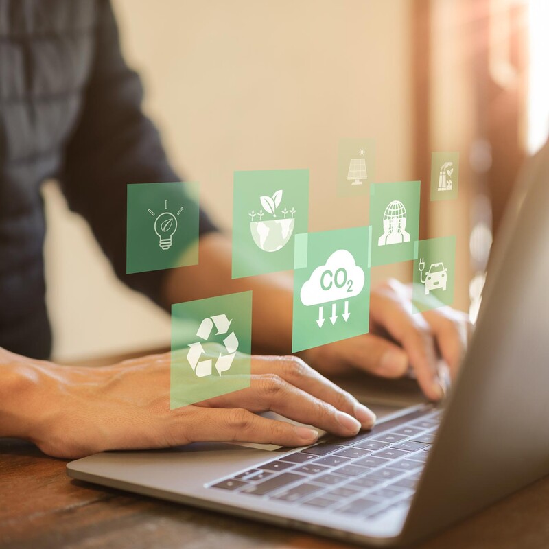 Person am Laptop mit Symbolen zum Thema Nachhaltigkeit