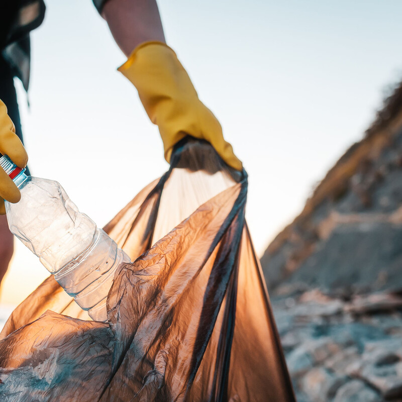 Person, die am Strand Müll einsammelt